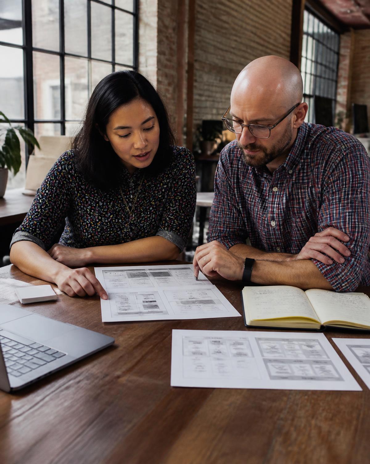 Two Helves consultants reviewing printed wireframes together